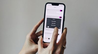 Hands holding an iPhone with inverted colours, adjusting the magnification settings