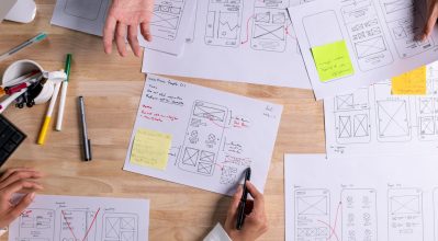 UX UI designers discussing and brainstorming on wireframes for a website and mobile app prototype.